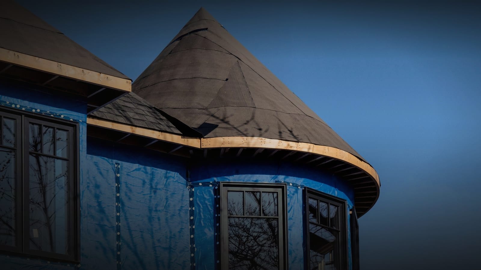 Blue weather-resistive house wrap taped and sealed around windows on a new-build exterior