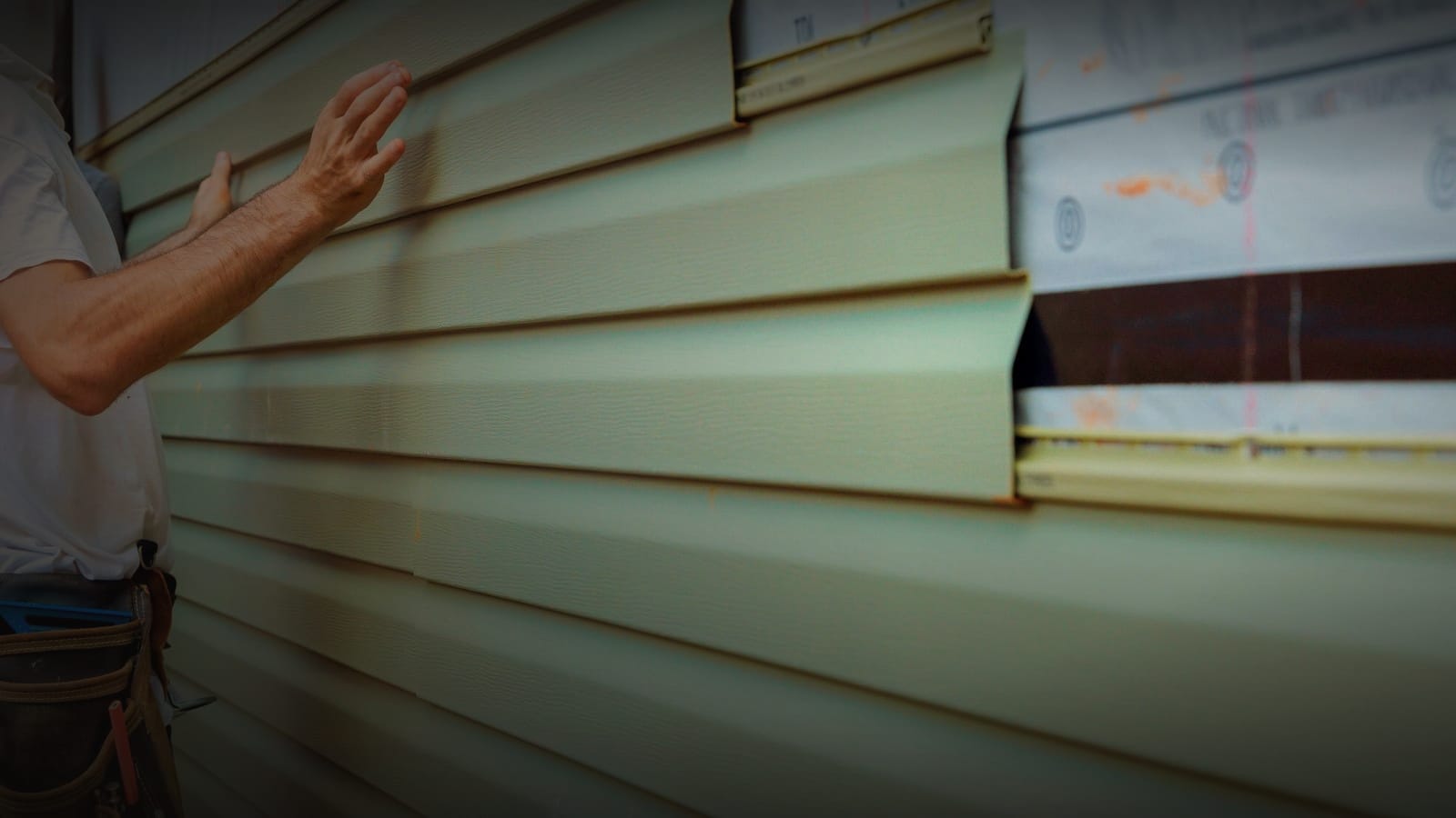 Installer aligning a siding board on an exterior wall during a re-clad